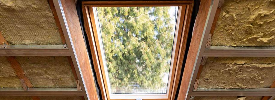 Ein Dachfenster, bei dem ringsherum Glaswolle zur Dämmung des Dachstuhls zu sehen ist.| Neue EU-Gebäuderichtlinie