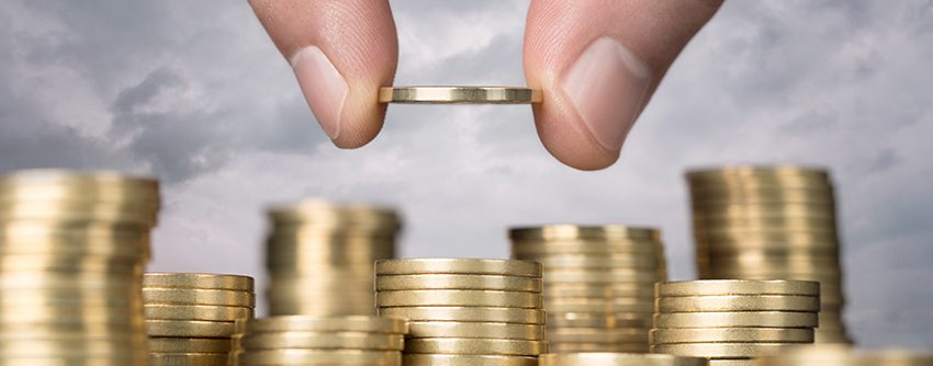 Savings, close up of male hand stacking golden coins over sky ba; Preisanstieg beim Bauen