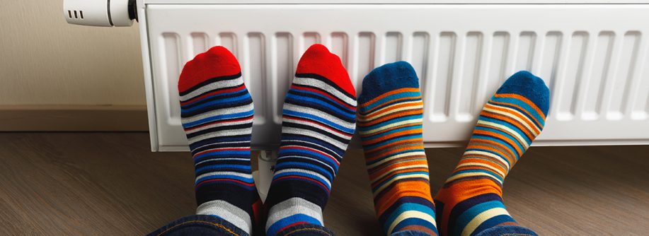 legs with colorful socks in front of heating radiator; Neues GEG