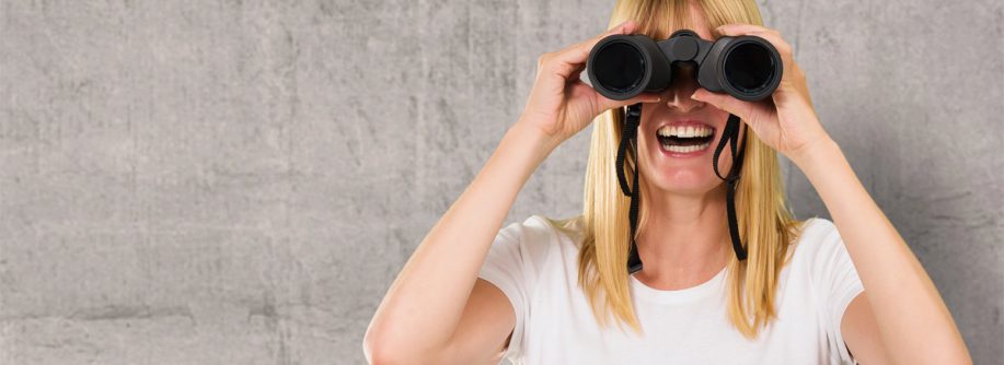 ein frau, die mit einem Fernglas nach einem Käfuer für ihre Immobilie Ausschau hält