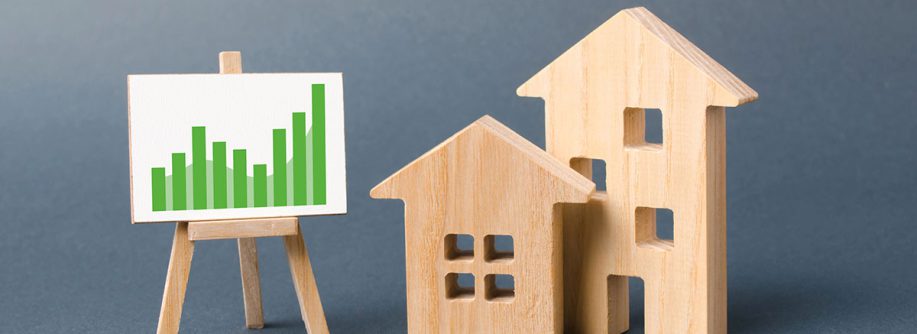 Holzhäuser und eine Lerntafel mit Statistiken als Symbol für die Immobilienwertermittlung