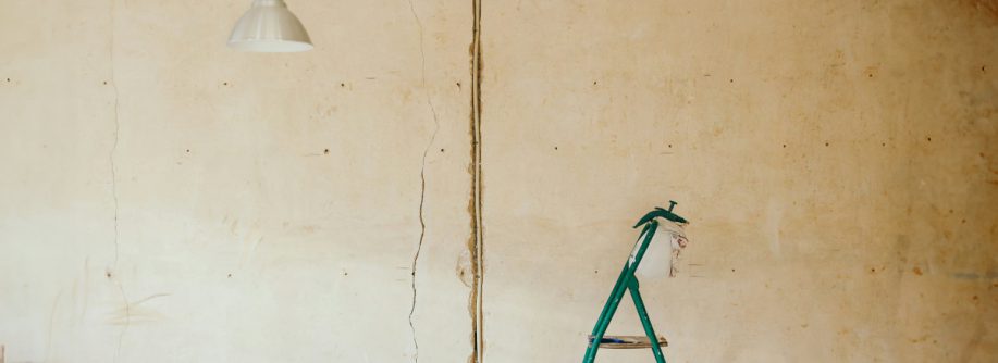 Vor einer unverputzten Wand steht eine Leiter, Renorvierungsarbeiten werden dargestellt