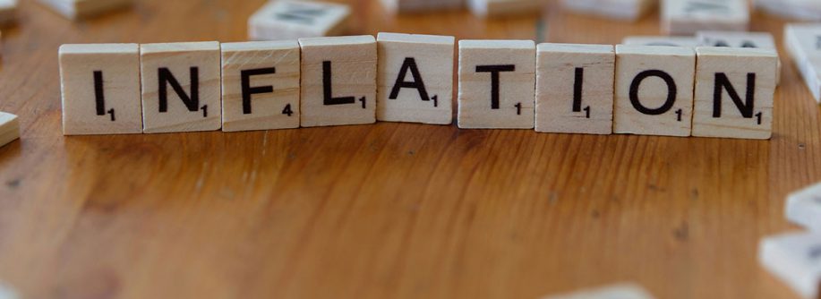 Auf einem Tisch liegt aus Scrabble-Buchstaben gelegt das Wort "Inflation" als Symbol für Immobilieninvestments während einer Inflation | Immobilieninvestment